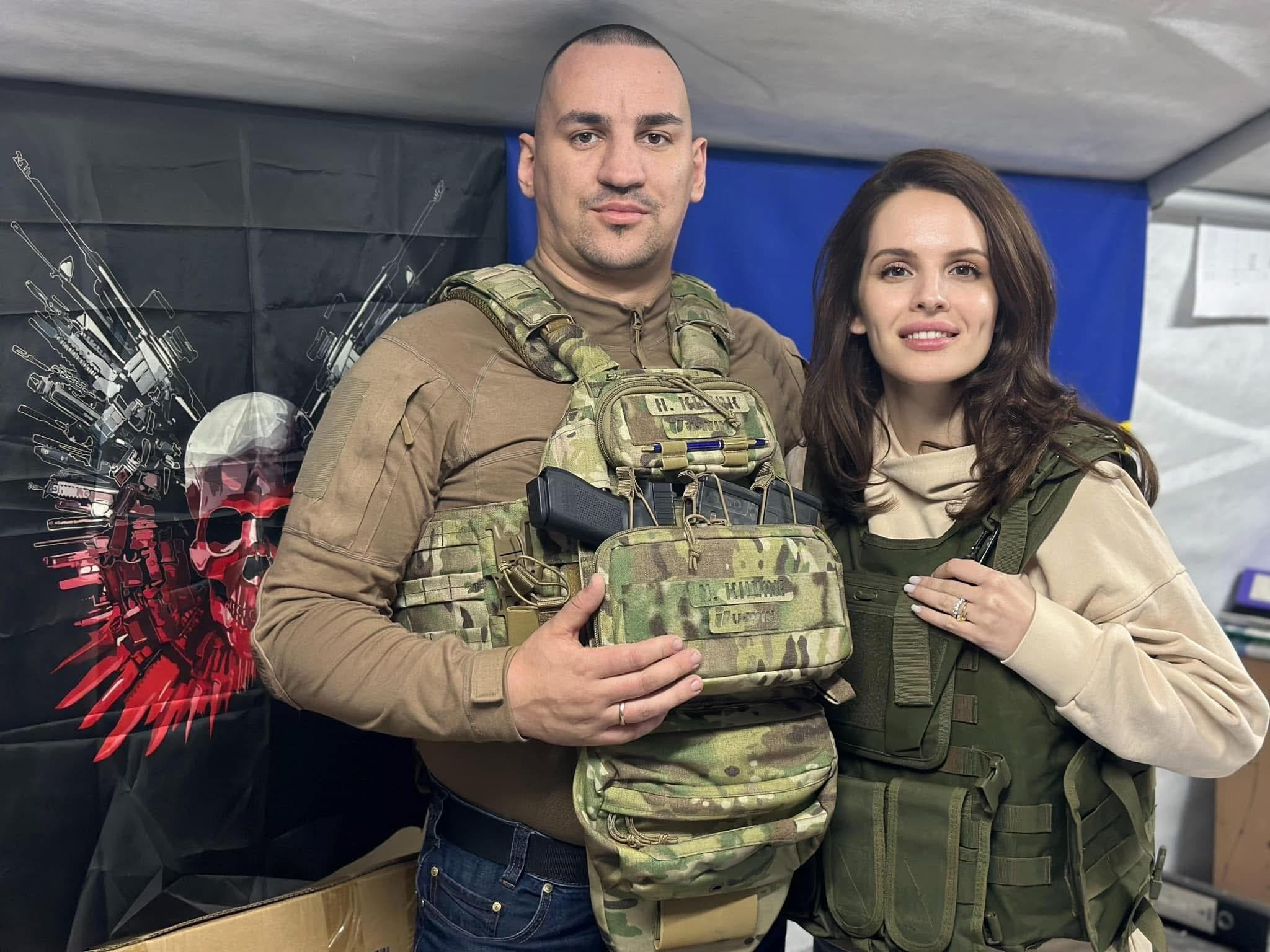 Anna Bon in body armour beside a soldier holding a tactical medical kit, inside a field tent.