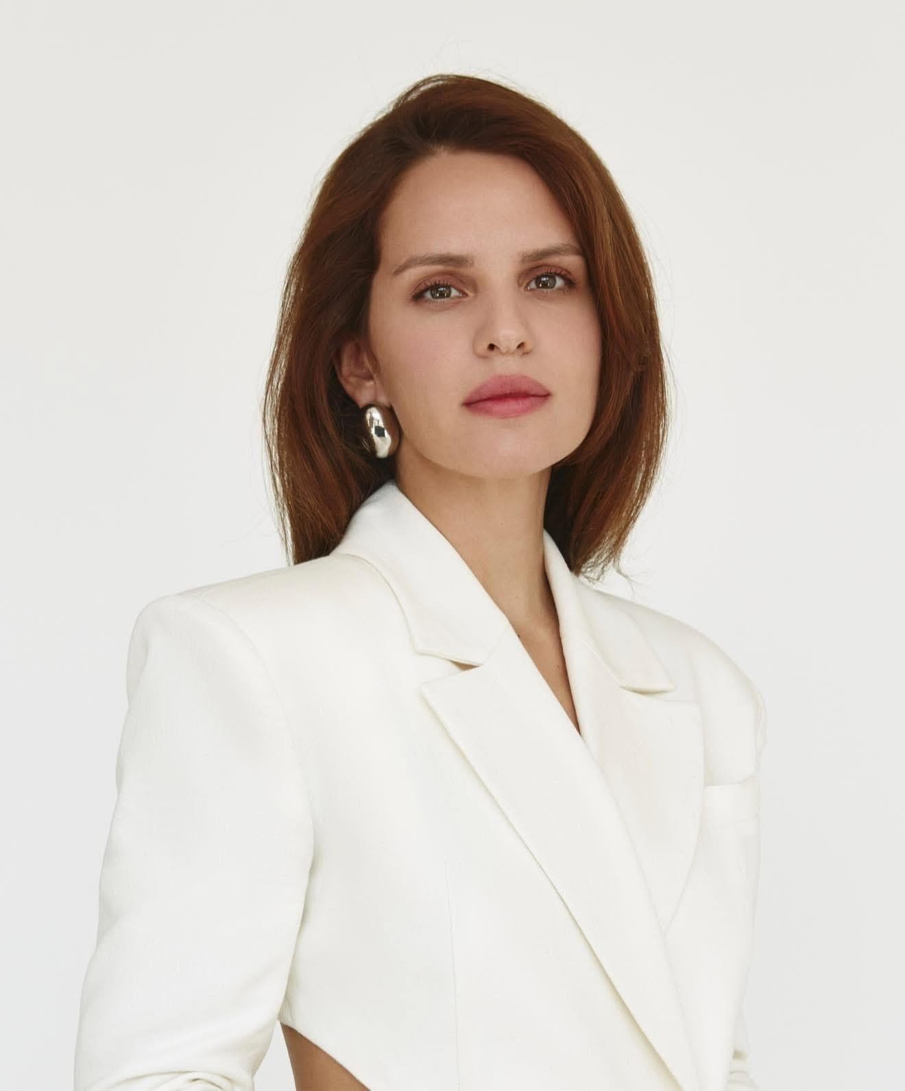 Anna Bon in a white suit against a white ground.