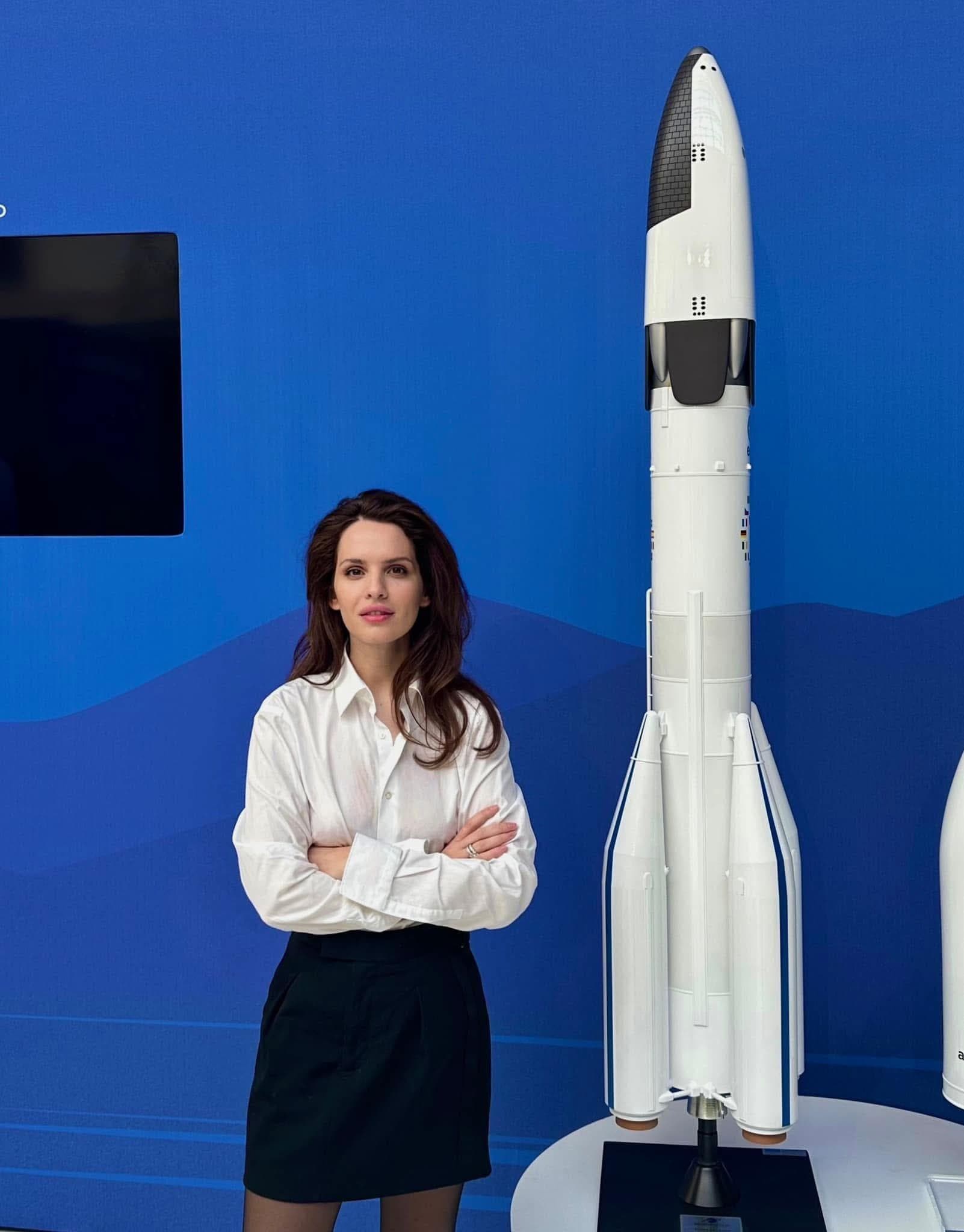 Anna Bon standing beside a model of a launch vehicle against a blue backdrop.