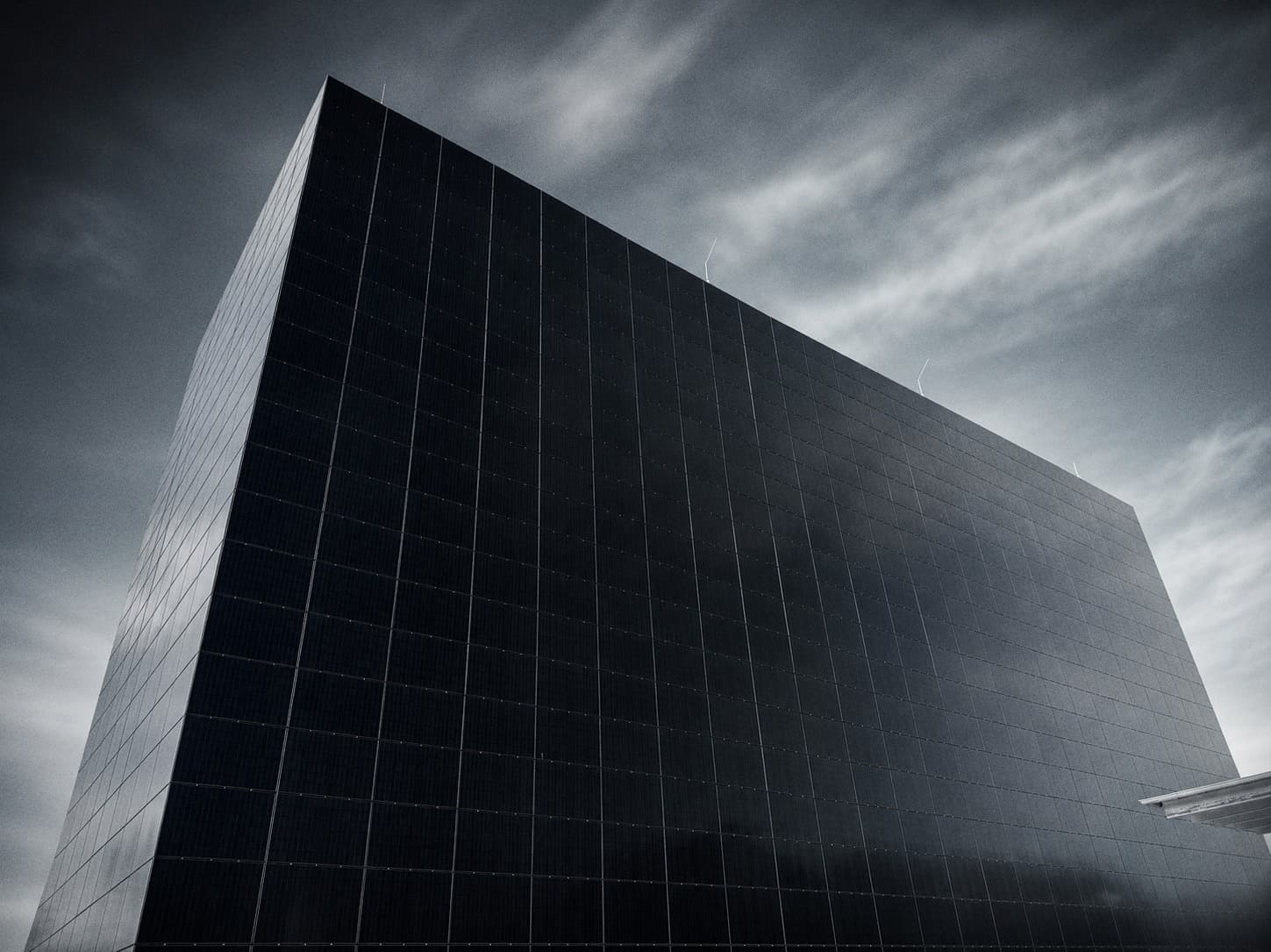 A dark, monolithic data-centre facade rising against an overcast sky.