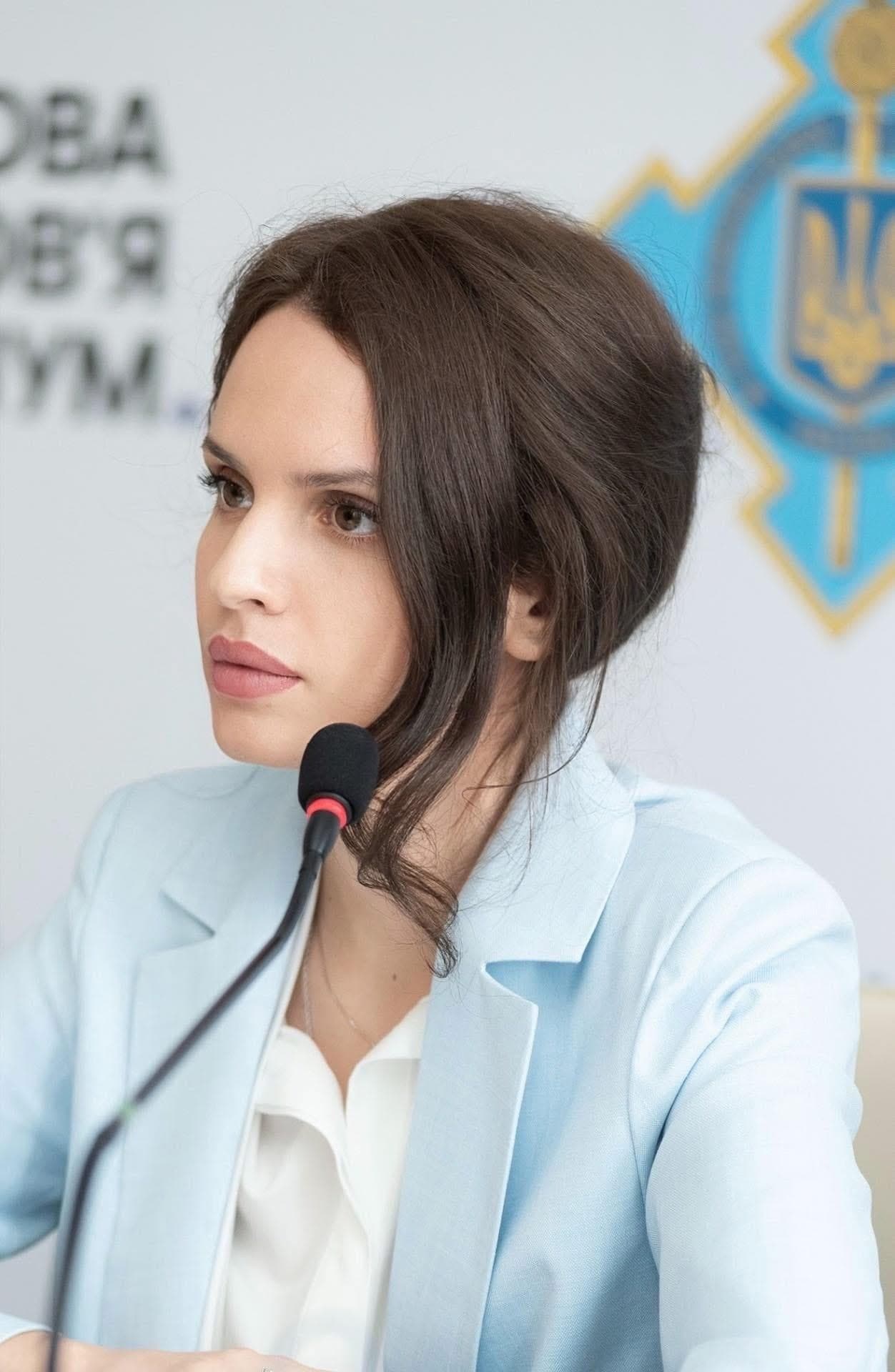 Anna Bon at a microphone on a panel, in a light-blue blazer.